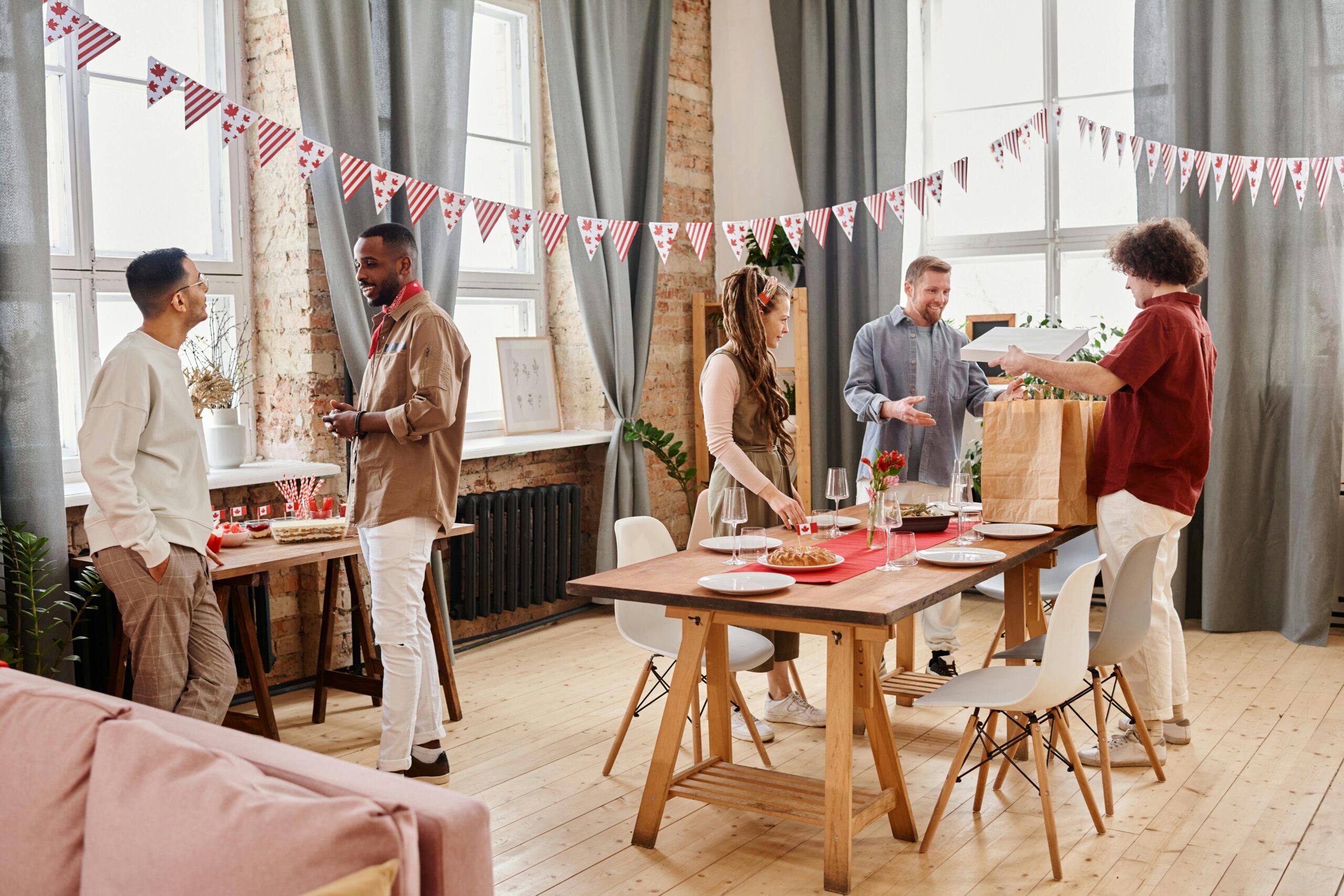 A diverse group of friends celebrating indoors with festive decorations and a table set for dining.
